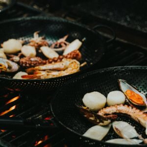 Close-up of a seafood medley grilling in a pan, featuring prawns, squid, and mussels. Perfect for cooking enthusiasts.