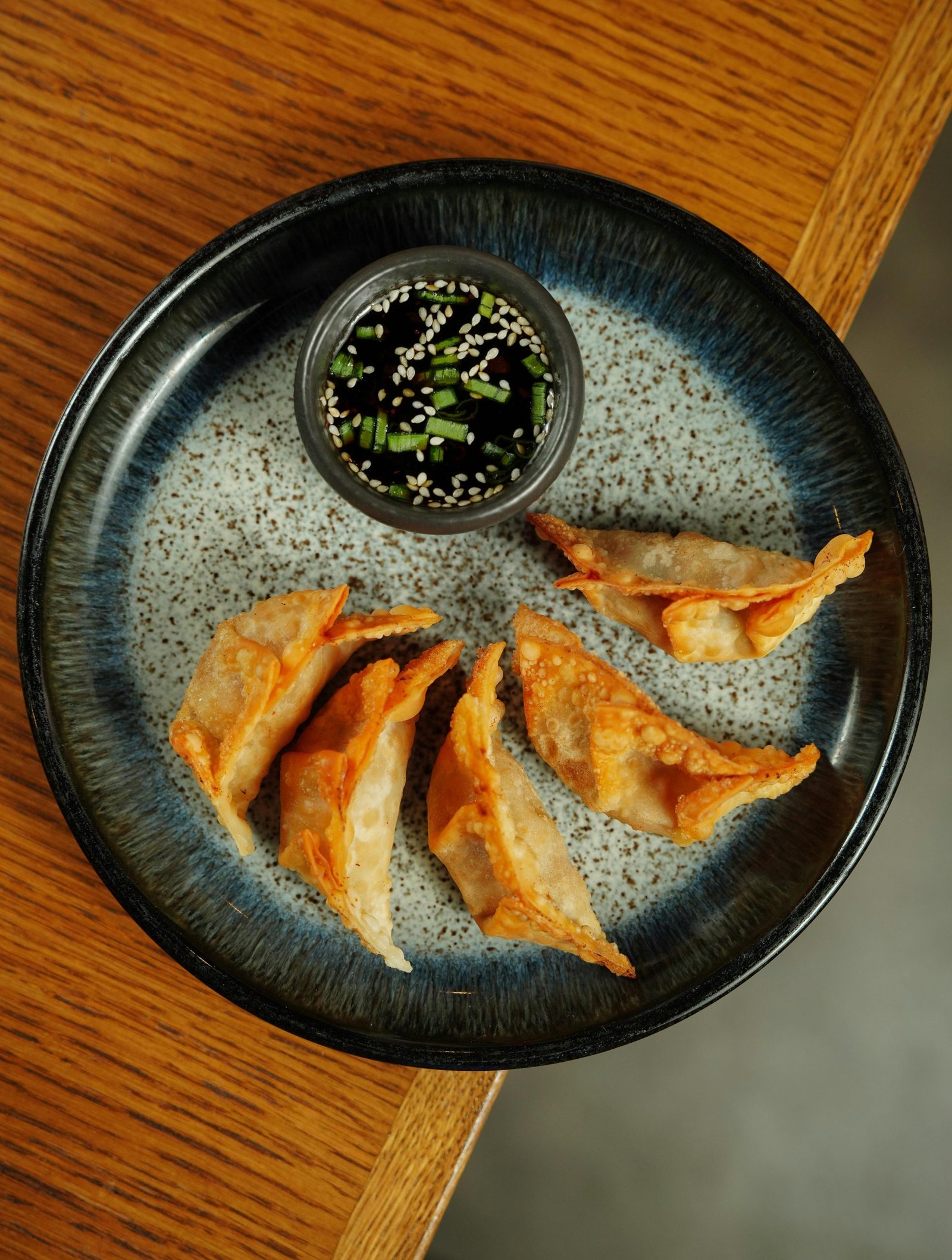 Delicious crispy dumplings served with soy dipping sauce on a ceramic plate.