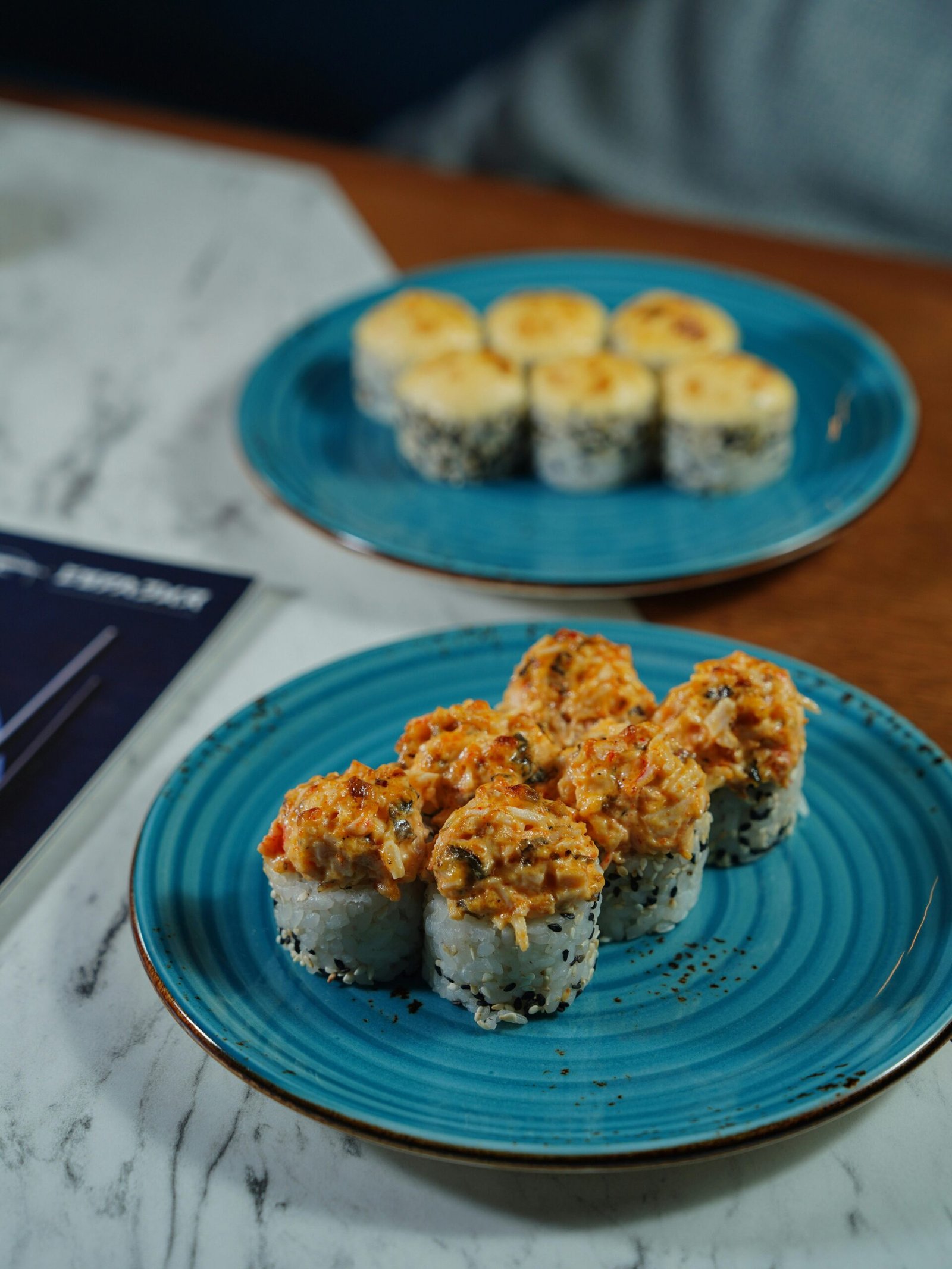 Sushi rolls elegantly plated on a marble table, showcasing gourmet indulgence.
