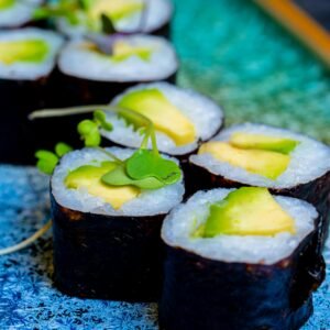 Vibrant vegetarian sushi rolls with avocado on a decorative blue plate. Perfect for healthy food themes.