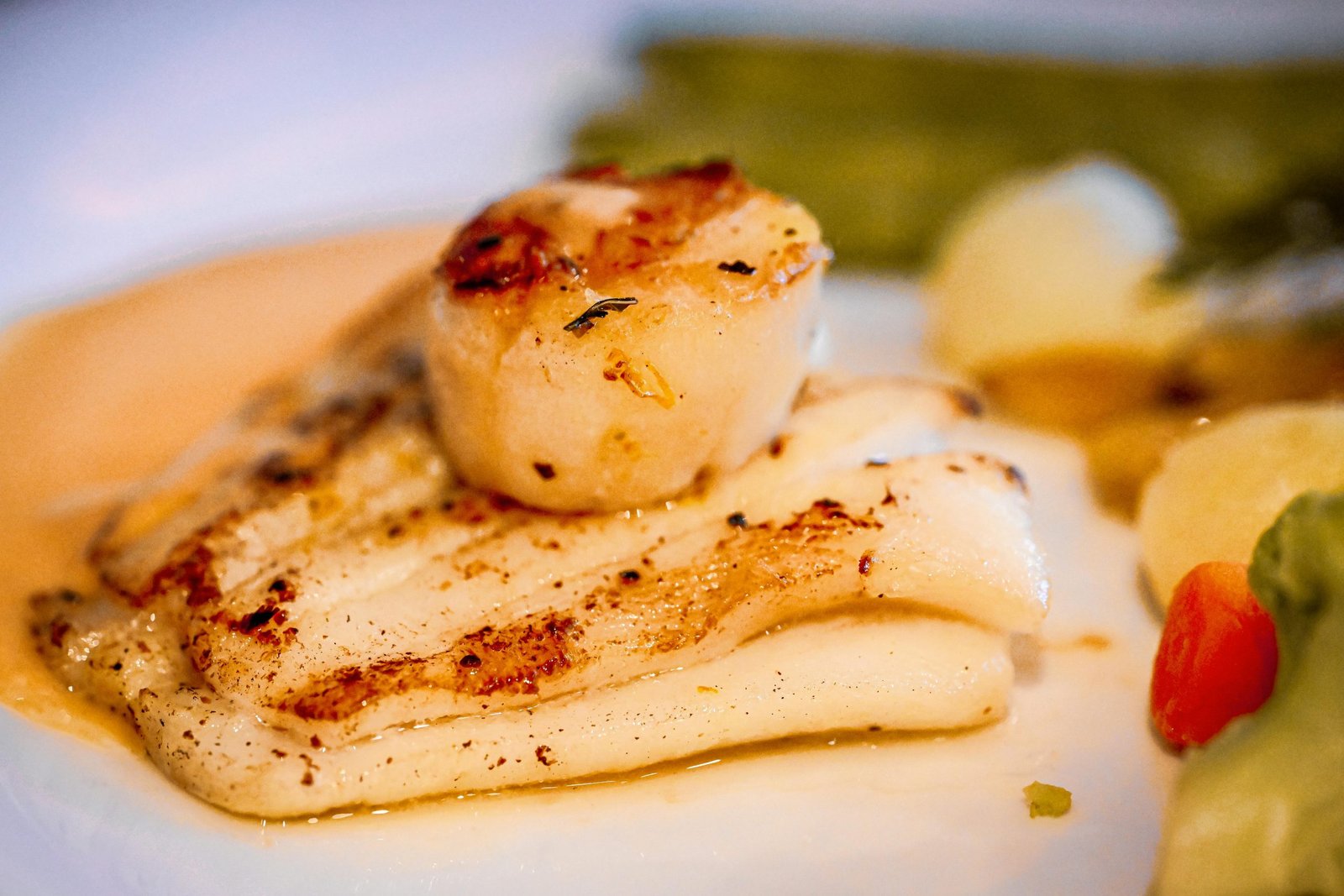 Delicious pan-seared scallops and grilled fish served with vegetables, ideal for culinary enthusiasts.