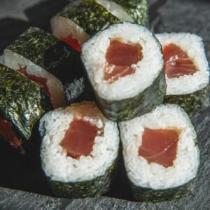 High-angle view of delectable tuna sushi rolls with nori wrap served on a slate plate.