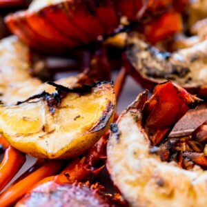 Delicious grilled lobster tails with lemon slices, perfect for seafood lovers.